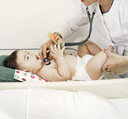 pediatra con estetoscopio revisando a bebé en pañal