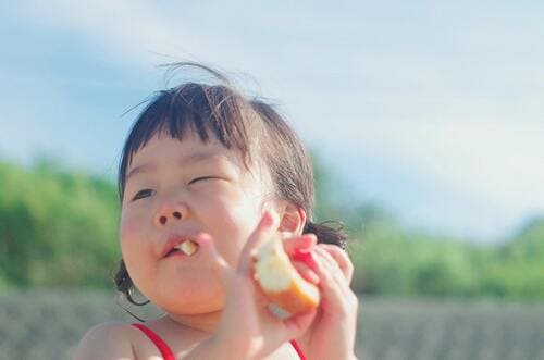 niña comiendo una manzana al aire libre